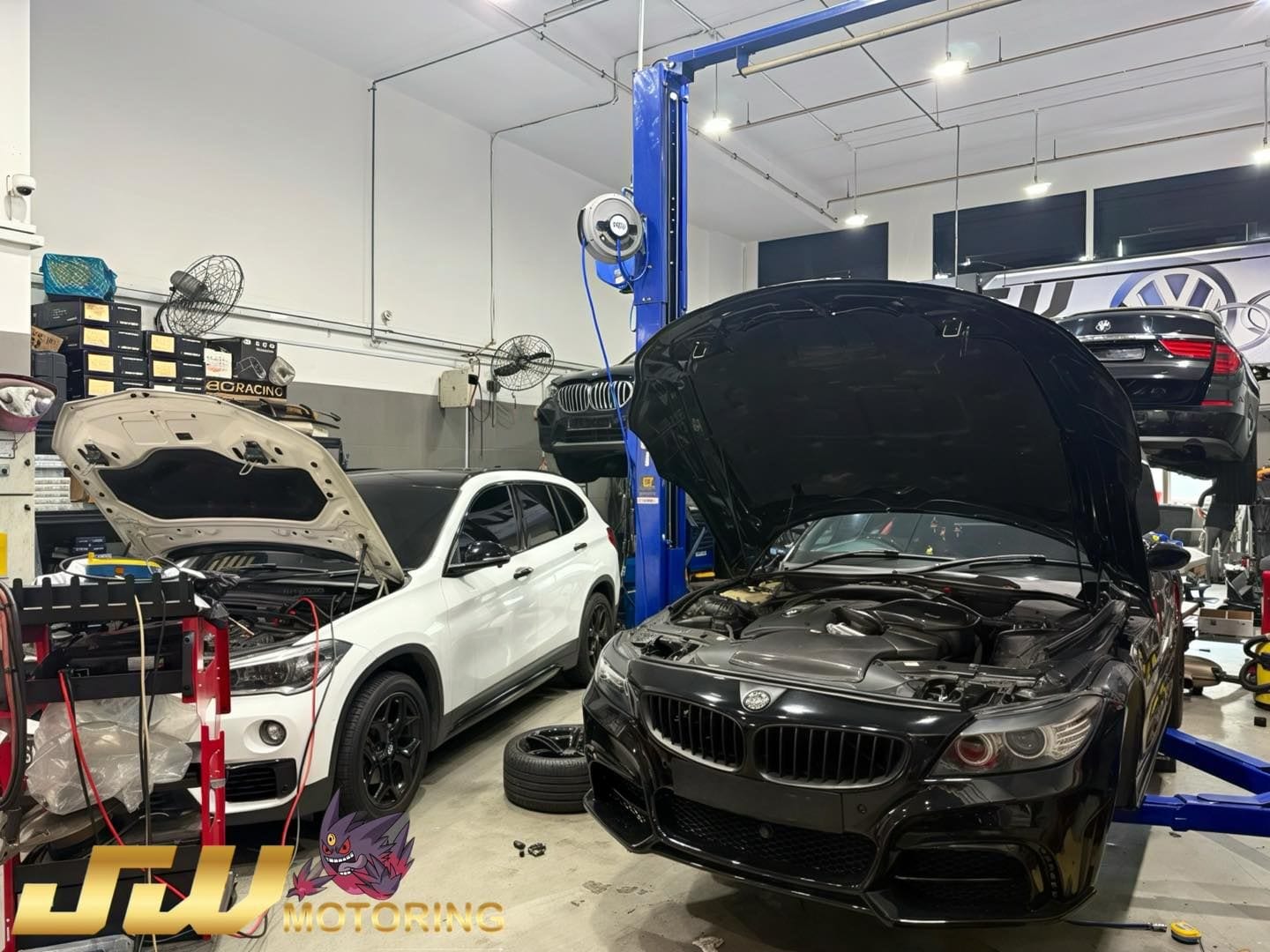 JW Motoring Kaki Bukit workshop — BMWs on lifts with hoods open, diagnostics connected, lifts and tooling for continental car servicing in Singapore
